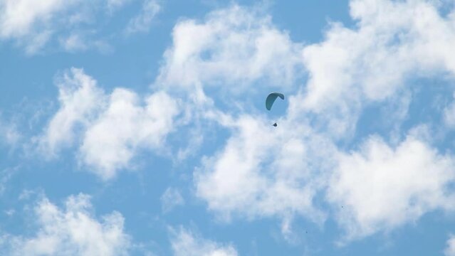 Closeup shot of parachute in front of clouds on blue sky. Adventure enthusiast doing paragliding in the sky. Adventure activities in Manali, Himachal Pradesh, India. Indian man enjoying Paragliding 