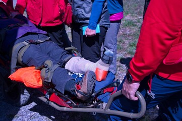 Paramedics from mountain rescue service provide first aid to person with broken leg