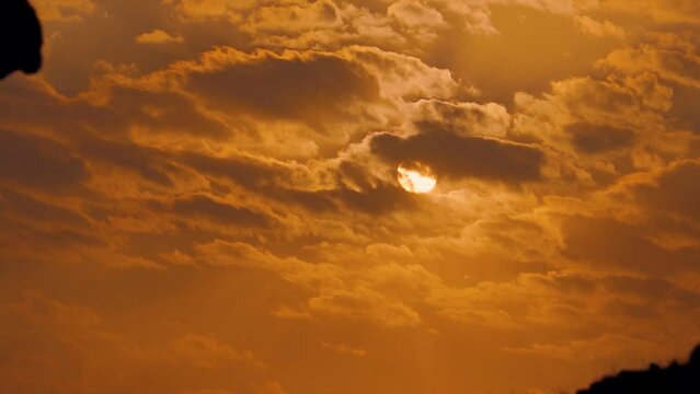 Closeup shot of sun behind the clouds during the sunset. Nature background. Sun hides behind the clouds during the sunset. Beautiful evening sky background. 