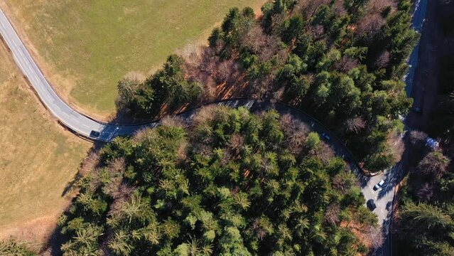 Filmmaterial einer Stra&szlig;e mit gef&auml;hrlicher Kurve in einem Waldst&uuml;ck mit fahrenden Autos in beiden Richtungen mit einer Drohne von oben, Deutschland