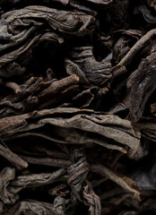 Dried black tea leaves as background.