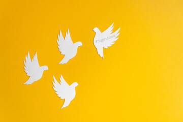 Four white paper dove birds as a symbol of peace isolated on yellow background. Peace to Ukraine....