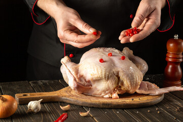 Cooking chicken in the kitchen with the hands of a cook. Before baking, the chef adds red viburnum to raw chicken. Asian cuisine.