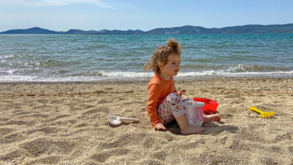 cute little girl playing with sand on beach