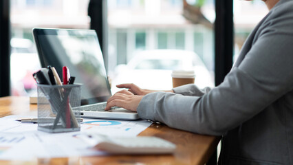 Business analyst concept the female officer typing financial information on the computer laptop