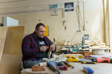 carpenter in a plaid shirt working with wood in the workshop