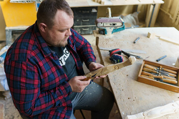 carpenter in a plaid shirt working with wood in the workshop