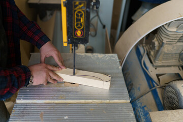 carpenter in a plaid shirt sawing wood on the machine