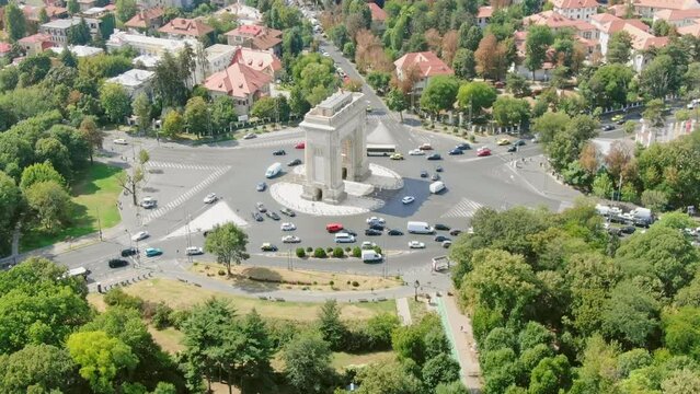 Aerial Video Drone Of Arc De Triomphe In Bucharest From Above, Arc De Triumf In Romania, Parc View From Above With Cars Driving By On A Sunny Summer Day With Green Trees Dolly Zoom