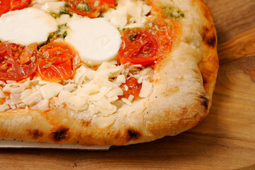 Premium high quality pizza with mozzarella cheese and tomato. Italian style dish with top products on wooden board and table.