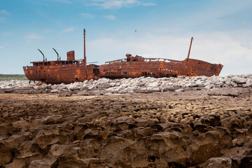 Plassey shipwreck on shore of Inisheer island. Aran islands, county Galway, Ireland. Rough stone coast and blue cloudy sky. Popular tourist landmark and attraction. Irish landscape