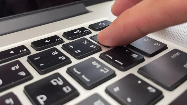 Typing on keyboard. Male hand finger press "delete" key button repeatedly on English - Thai laptop keyboard. Digital nomad professional hand on laptop close up - technology concept