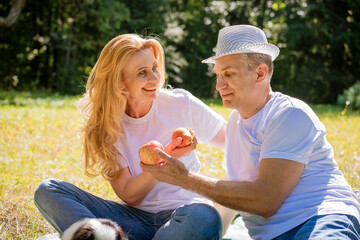 Joyful caucasian couple sits in city park. Man and woman outdoors, hugging, smiling and laughing on a sunny summer day in casual light clothes. Happy couple retired concept