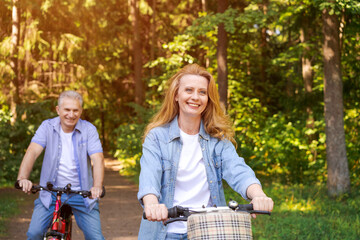 Cheerful active senior couple with bicycle walking through park together. Perfect activities for...