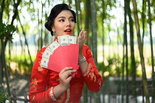 Asian pretty Chinese woman in cheongsam holding envelopen with banknote