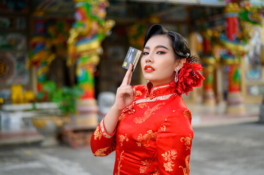 Asian beautiful woman wearing a cheongsam show credit card at shrine on Chinese New Year
