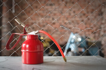 Red oil can on the workbench on the blurred motorbikes background close up.