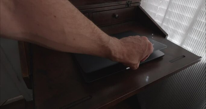 Hand opens laptop in home office with simple and modern desk. Computer screen green for chroma key.
