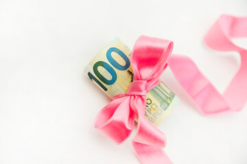 Concept, money as a gift, win or bonus. Takes or gives pile of 100 dollar bills tied with red ribbon with bow.