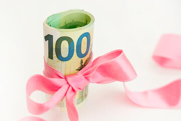 Concept, money as a gift, win or bonus. Takes or gives pile of 100 dollar bills tied with red ribbon with bow.