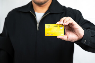 Young male customer holding showing yellow credit card for payment close up on white background. cashless technology payment concept