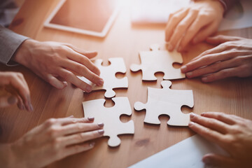 Buisnesswomen and buisnessmen working together while putting together puzzles.