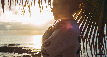 Side portrait of serene and peaceful pretty lady agains a beautiful sunset on the ocean. Adult...