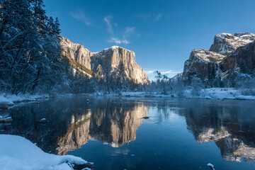 Impression of the mountains surrounding Yosemite Valley, during golden hour, being reflected in the Merced river.