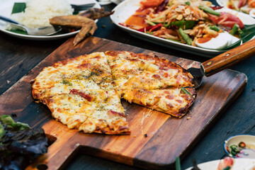 Homemade pizza with spicy Asian food on wood table