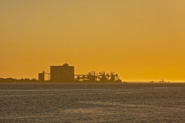 Silhouette of Silo`s and cranes against golden sunset sky in the port of Lisbon, Portugal