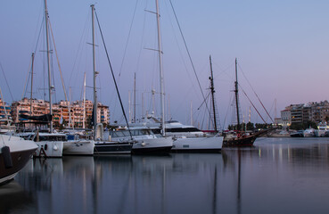 Marine theme, sail boats, yachts on the pier, reflection on the water, in the evening, summer day in Greece
