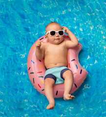 small child swims in the pool on an inflatable ring - 501692708