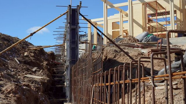 Tied iron rebar close up. Reinforcing bar is binded before the concreting on the construction site. Workers concrete a retaining wall at the construction site of a wooden house