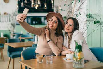 women friends on coffee break at cafeteria using mobile phone