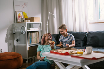 mother and her son having fun at home eating pizza