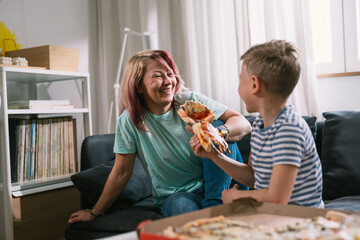 mother and her son having fun at home eating pizza