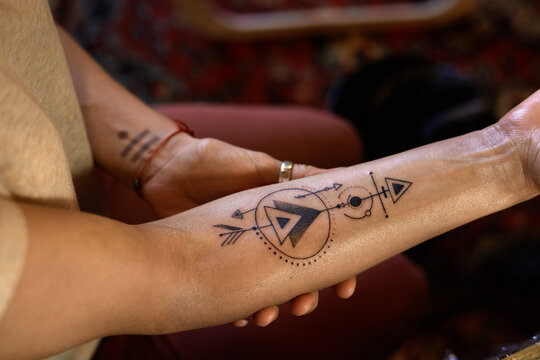 Close-up view of unrecognizable woman demonstrating just finished creative arrow tattoo on her hand