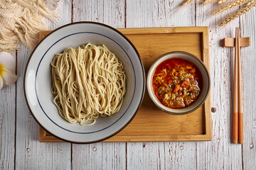 Asian noodles with crab roe and spicy sauce on wood table.