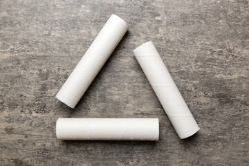 Empty toilet paper roll on colored background. Recyclable paper tube with metal plug end made of kraft paper or cardboard in the form of a recycling sign