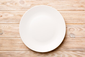 Top view of empty light plate on wooden background. Empty space for your design