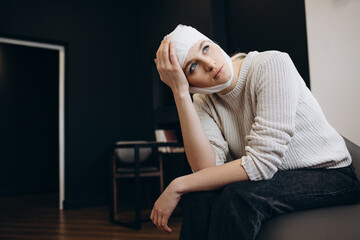 Young beautiful woman with a gauze bandage on her head and chest, on black background