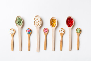 Top view Variety of vitamin and mineral pills in wooden spoon on Colored background. Top view of assorted pharmaceutical medicine pills. Dietary supplement healthcare product