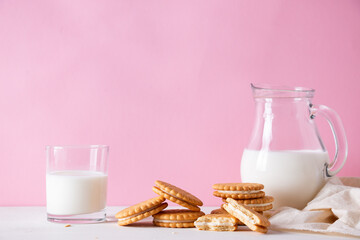 Sandwich cookies and a glass of milk on a pink background. The concept of breakfast and a quick snack.