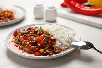 Plate of rice with chili con carne on white wooden table