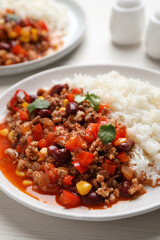 Plate of rice with chili con carne on white wooden table