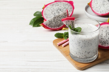 Glass of tasty pitahaya smoothie with fresh mint on white wooden table, space for text