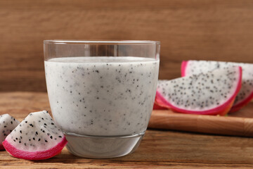 Glass of tasty pitahaya smoothie and fresh fruit on wooden table, space for text