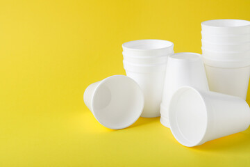 White styrofoam cups on yellow background, space for text