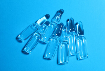 Pharmaceutical ampoules with medication on light blue background, flat lay