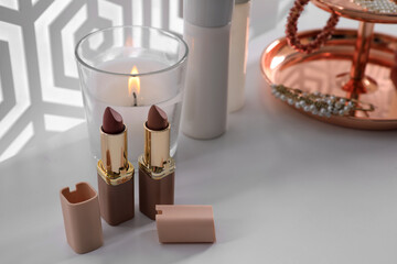 Fototapeta Burning soy candle and lipsticks on white table indoors obraz